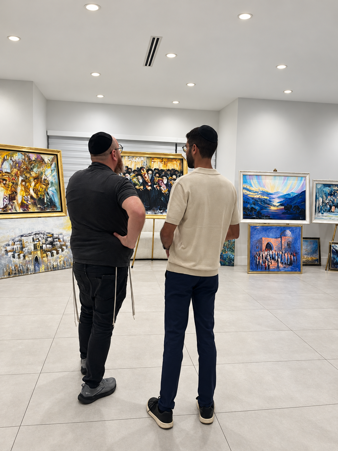 Two visitors looking at framed Judaic paintings inside a Judaic Art Exchange gallery show.